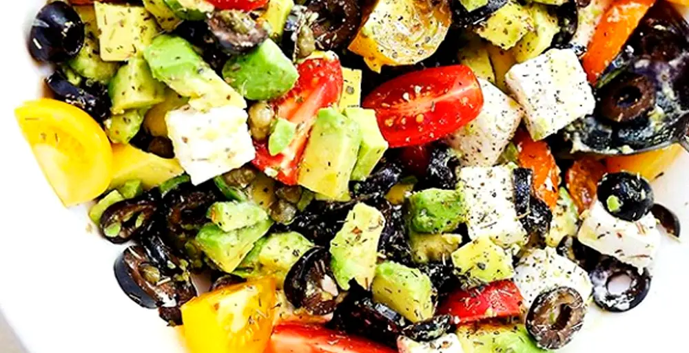 Pentru această salată cu roșii, brânză și avocado tăiem roșiile, castravetele, ceapa; curățăm avocado și-l tăiem cuburi. Brânza se taie și ea cuburi sau se poate rade pe răzătoarea mare, după preferință.